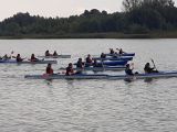 Uczniowie liceum płyna w dwuosobowych kajakach po jeziorze. Wszyscy mają na sobie kamizelki.