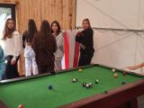 Uczennica licum pochyla się nad zielonym stołem bilardowym .W tle grupa dziewcząt.