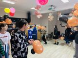 Grupa gimnazjalistów stoi w kręgu z pomarańczowymi balonami w dłoniach