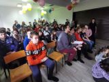 Grupa uczniów siedzi na krzesłach w dużej sali
