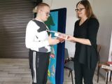 Kobieta w okularach wręcza dyplom gimnazjaliście w biało - czarnej bluzie