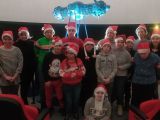 Grupa uczniów w czerwonych czapkach w planetarium. W tle niebieski teleskop