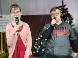 Chłopak i dziewczyna w okularach śpiewają trzymając w dłoniach mikrofony