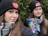 Dwie dziwczyny w czarnych czapkach z serduszkami stoją obok siebie