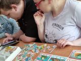 Dwoje gimnazjalistów siedzi przy ławce szkolnej. Na ławce rozsypane kolorowe puzzle