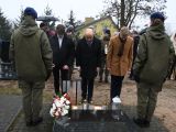 Mężczyzna i dwóch uczniów liceum stoją przed grobem. Wszyscy mają opuszczone głowy.
