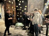 Mężczyzna w czarnej koszuli mówi do stojących przed nim uczniów liceum.