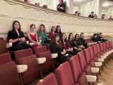 Uczniowie liceum siedzą na czerwonych fotelach w dwóch rzędach w sali teatru.