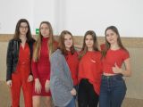Pięć dziewczą z liceum stoi przy ścianie na korytarzu. Wszystkie mają czerwone bluzki.