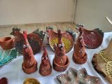 Ceramiczne kury w kolorze ceglastym na stole nakrytym białym obrusem