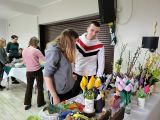 Dwoje gimnazjalistów ogląda wielkanocne ozdoby leżące na długim stole