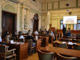 W sali przy kilkumastu brązowych stołach siedzą uczniowie liceum. Patrzą na ekran projekcyjny, który wisi przed nimi na...