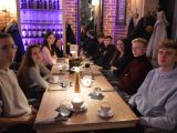 W restauracji przy długim stole po obu stronach siedzi dziewięcioro uczniów liceum.