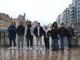Dzieięcioro uczniów liceum stoi na  moście przy barierce. W tle rzeka. Po obu stronach rzeki zabudowania.