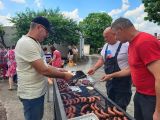 Troje mężczyzn przy dużym grillu. Na grillu kiełbaski