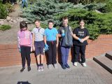 Pięcioro uczniów szkoły podstawowej z niebieskimi rękawiczkami na dłoniach. Uśmiechniety chłopiec stojący w środku trzyma...