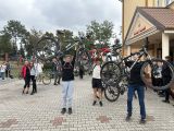 Na dziedzińcu przed szkołą stoi grupa uczniów. Trzech chłopaków unosi rowery do góry.