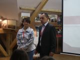 Kobieta w okularach stoi obok mężczyzny w ciemnej marynarce.