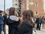 Trzy dziewczyny z liceum trzymają metalowy łańcuch. W tle budynek z czerwonej cegły.