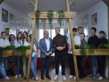 Na korytarzu szkolnym, między drewnianymi filarami, w rzędzie stoją trzy licealistki i sześci licealistów, między nimi dwie...