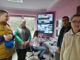 Czworo uczniów w biurze. W tle ekrany monitoringu i kobieta siedząca przy biurku