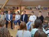 W rzędzie na krzesiałch siedzi siedem osób: dwie dziewczyny, dwóch mężczyzn, kobieta i dwóch chłopaków.