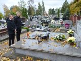 Trzech uczniów liceum w czarnych ubraniach stoi przed grobem na cmentarzu.