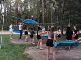Nastolatki przerzucające balony z wodą nad siatką na boisku do siatkówki plażowej.