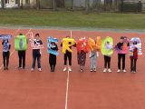 Pośrodku boiska dziesięcioro uczniów liceum stoi w rzędzie. Przed sobą trzymają kolorowe litery tworzące napis "Tolerancja".