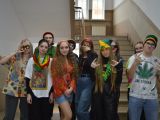 Przed schodami na korytarzu szkolnym stoi duża dziesięcioro uczniów liceum. Wszyscy ubrani są na kolorowo.