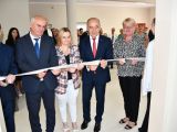 Dwóch mężczyzn w garniturach, dwie kobiety i uczeń w garniturze przecinają biało-czerwoną wstęgę.