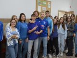 Grupa uczniów liceum stoi przy ścianie na korytarzu szkolnym. Wszyscy mają niebieskie ubrania.
