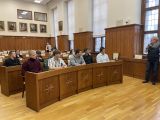 W sali w dwóch dużych ławach siedzi dziesięcioro uczniów liceum i dwie kobiety. Na ścianach drewniana boazeria.