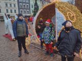 Dzieci stoją przed  świąteczną karetą przystrojoną kolorowymi lampkami.