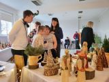 Czworo uczniów i uśmiechnięta kobieta w ciemnym swetrze. Przed nimi długi stół z wyłożonymi na nim kolorowymi ceramicznymi...