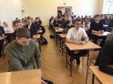 Uczestnicy, siedzący przy stolikach , słuchają instrukcji przed rozpoczęciem konkursu.