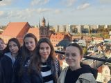 Grupa dziewcząt na balkonie. W tle panorama i zabudowania miasta.