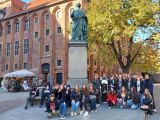 Grupa młodziezy siedzącej wokół pomnika Kopernika.