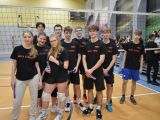 Dziesięcioro uczniów liceum stoi w grupie na sali gimnastycznej przy siatce. Wszyscy mają czarne koszulki.