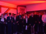 Grupa kilkunastu nastolatków na scenie Przyciemnione czerwone światło. Portret Władysława Łokietka w tle.