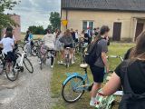 Na podwórku między domami stoi grupa licwliatów, każdy ma przy sobie rower.