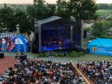 Widok z góry na scenę. Przed scenąsiedzi widownia. w tle sceny drzewa.