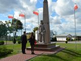 Dwoje nastolatków czarnych ubraniach stoi przed pomnikiem Władysława Łokietka W tle biało-czerwone fagi.