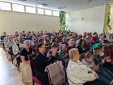 Klaszcząca grupa ludzi siedząca na krzesłach w dużej auli