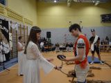 Na pierwszym planie dziewczynka i chłopiec w białych sztach w tle sala gimnastyczna